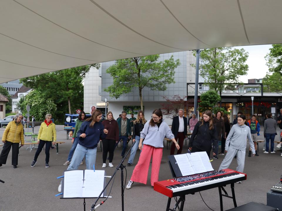 Männer und Frauen in Tracht tanzen im Kreis während der Langen Nacht der Kirchen in Weinfelden.