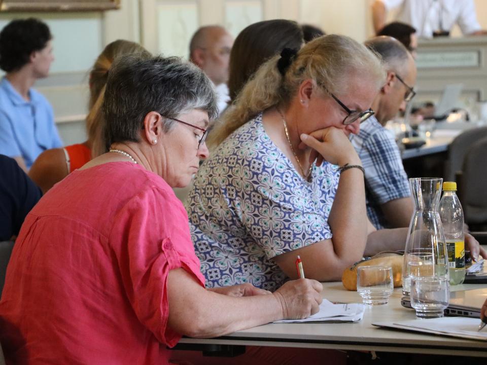 Personen schreiben während der Sitzung der Katholischen Landeskirche Thurgau Notizen