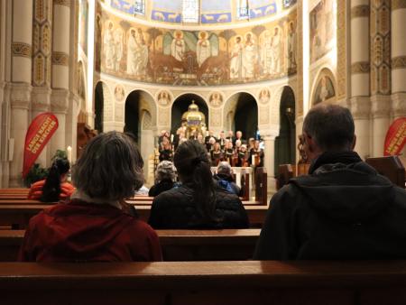 Besucherinnen und Besucher stehen singend neben den Chormitgliedern der Pfarrei St. Johannes.