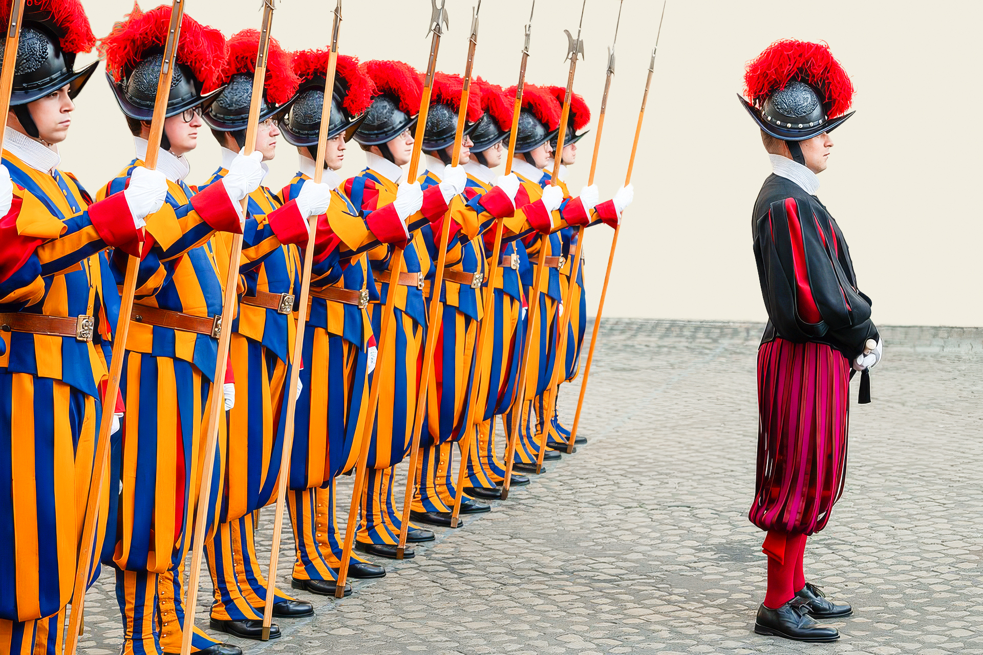 eine Reihe Schweizergardisten, davor ein Vorgesetzter in einer rot-schwarzen Uniform