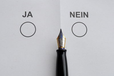 Stimmzettel mit Ja/Nein-Feldern, dazu eine Füllfeder